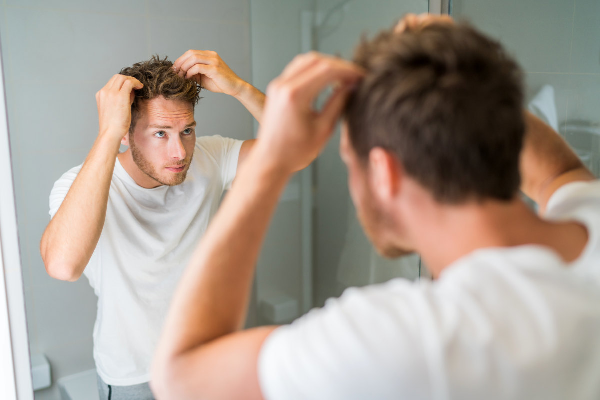 Hair loss man looking in bathroom mirror | Finasteride FAQ: How To Prevent Hair Loss, Side Effects, Uses | oral finasteride