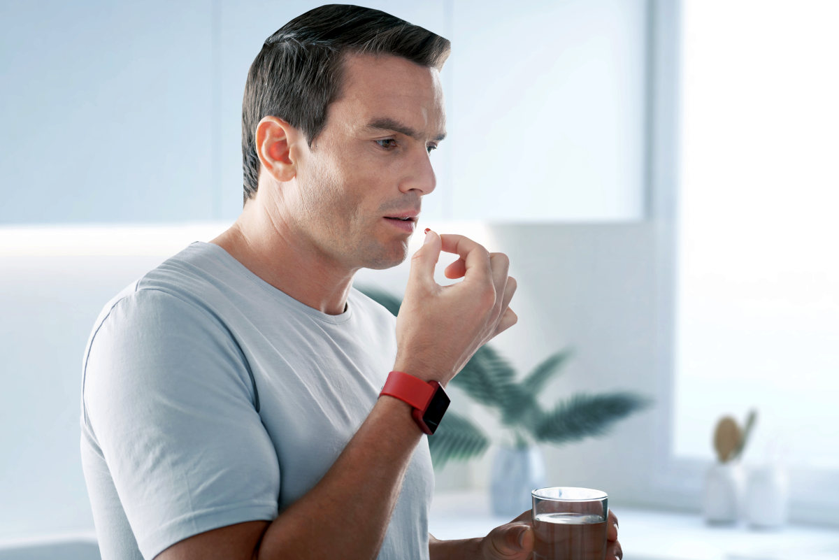 Handsome young man standing with a glass of water and taking pills | Tadalafil FAQ: How Long The Daily ED Pill Lasts (And Common Questions) | tadalafil dosage